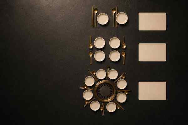 Overhead flat-lay of cream place settings with gold utensils in three groups: two, four, and a ring of about a dozen around a central grill; three blank cards at right.