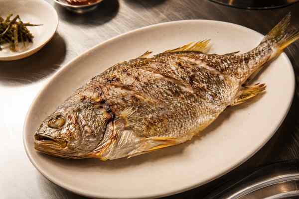 Finished Jogi Gui Grilled Yellow Croaker presented in a warm Korean dining setting.