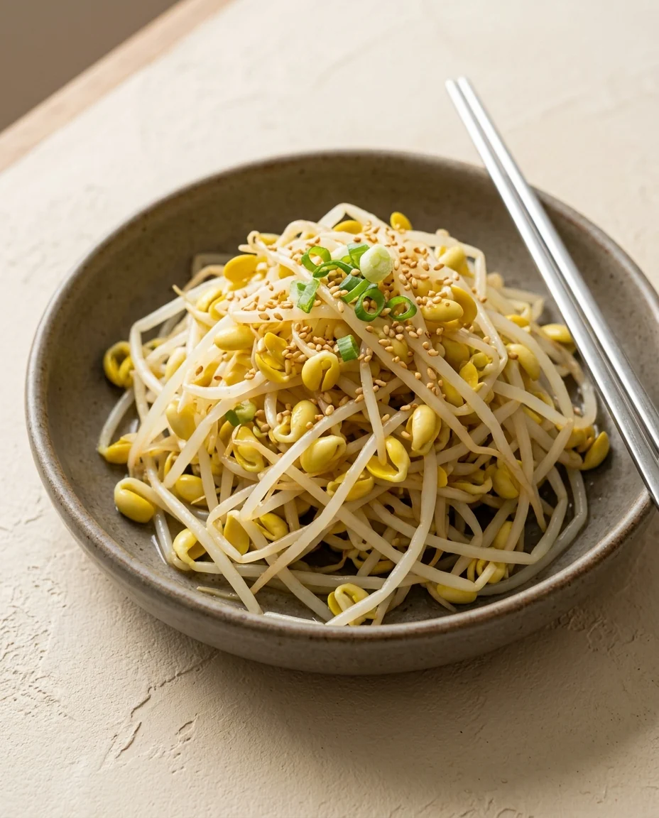 White soybean sprouts with yellow heads, scallion rings, and sesame in a bowl.